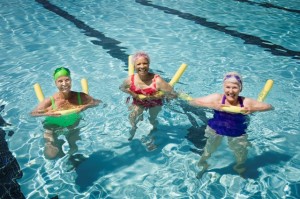 Senior woman swimmers in pool with flotation devices